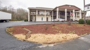 Un motel composé d’un bâtiment à deux étages, d’un espace de stationnement couvert et d’un jardin aménagé à l’avant.
