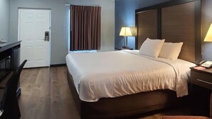 Une chambre d’hôtel avec un grand lit, des lampes de chevet, un bureau et une porte.