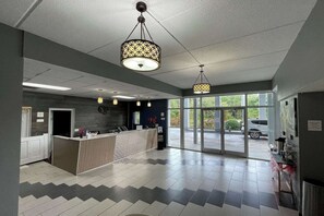 Un espace d’accueil comprenant un comptoir, une grande fenêtre et un plafond orné de luminaires suspendus.