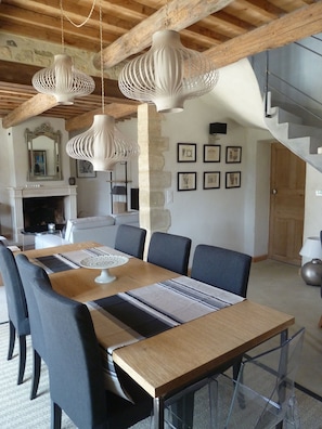 A dining area with a wooden table, chairs, and hanging pendant lights.