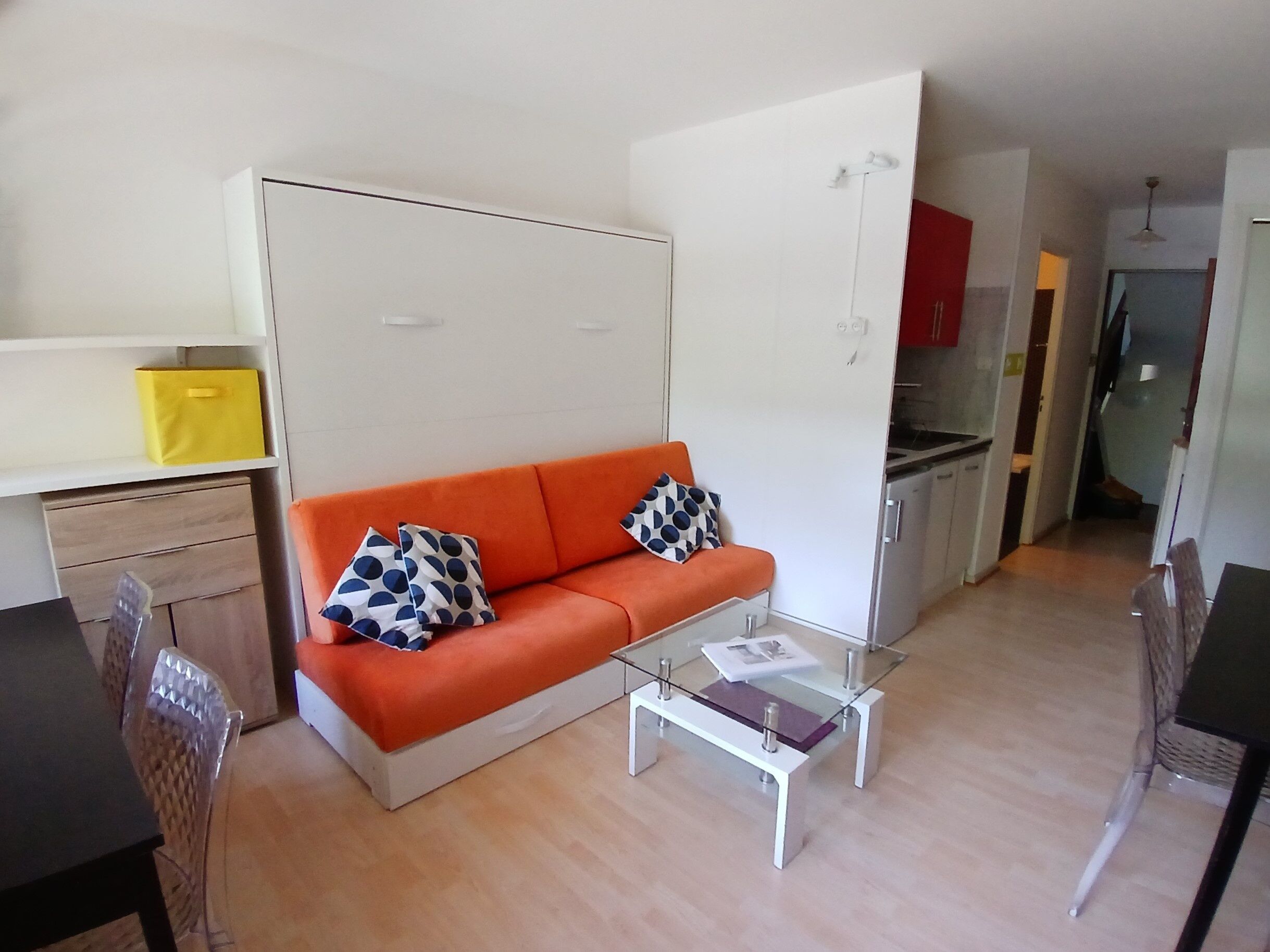 Ein kompakter Wohnbereich mit Sofa, Glastisch, Esstisch und Küchenzeile.
