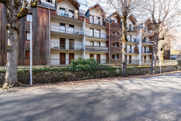Un hôtel à plusieurs étages, doté de balcons, de façades en bois et situé le long d’une rue pavée.