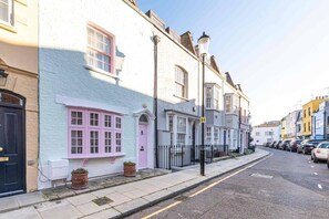 A row of terraced houses with a sidewalk and parked cars. - Godfrey Street (London)