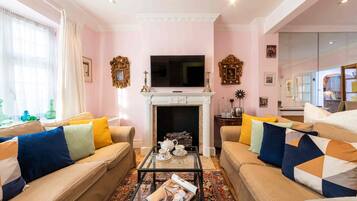 A living room with beige sofas, a fireplace, and a television.