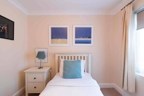 A bedroom with a bed, a nightstand, a lamp, and two framed pictures on the wall.
