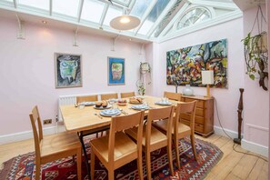 A dining area with a wooden table set for six, surrounded by chairs. - Godfrey Street (London)