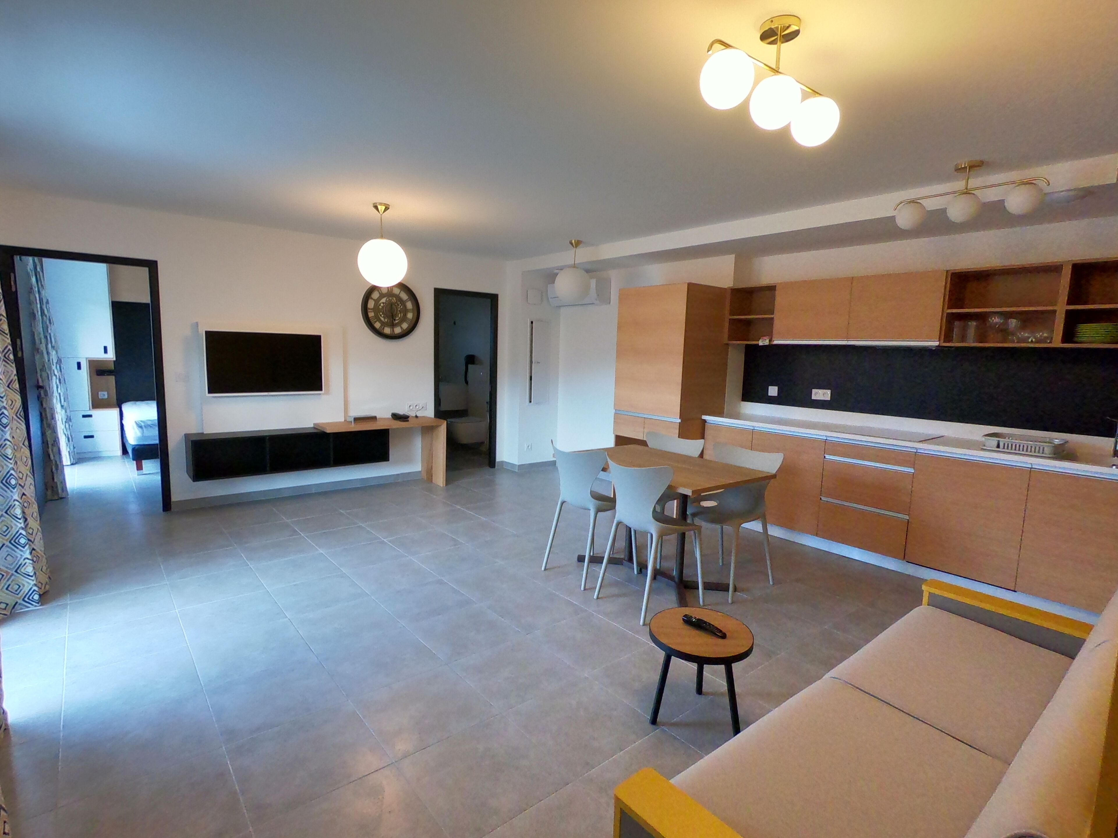 Una sala moderna con televisor, zona de estar y cocina con armarios de madera.