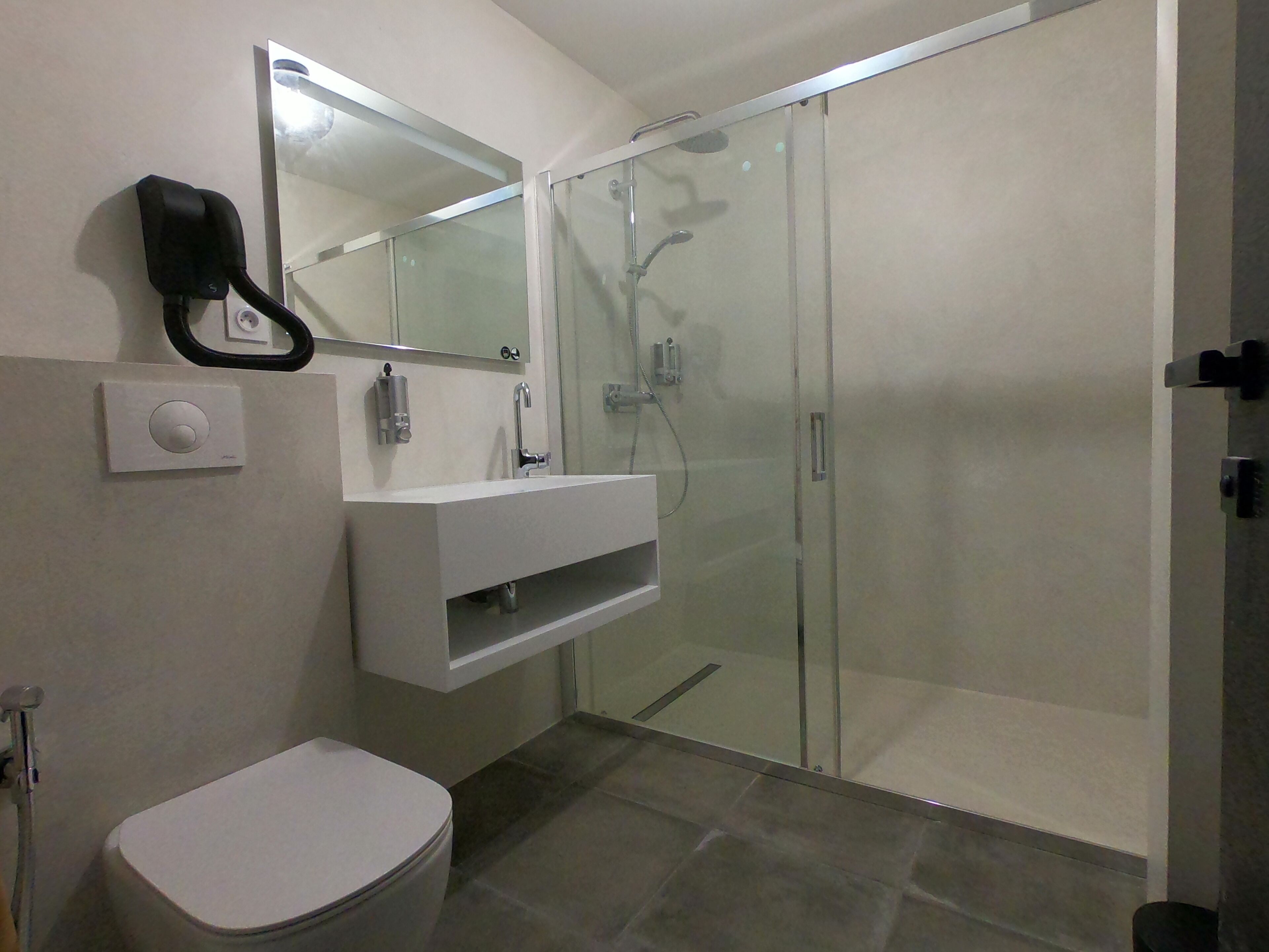 Ein modernes Badezimmer mit Duschkabine aus Glas, einem weißen Waschbecken und einer Toilette.