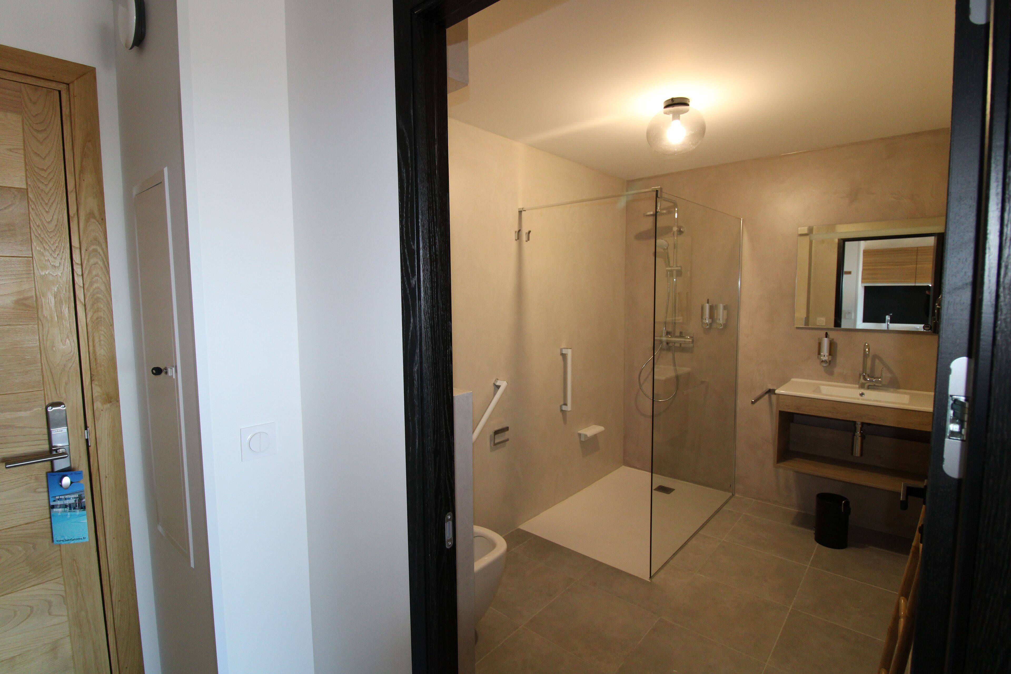 Un baño moderno con cabina de ducha de vidrio, inodoro y lavamanos con espejo superior.