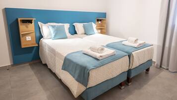 Una cama doble con cabecera azul y dos mesitas de noche, cada una con un estante.