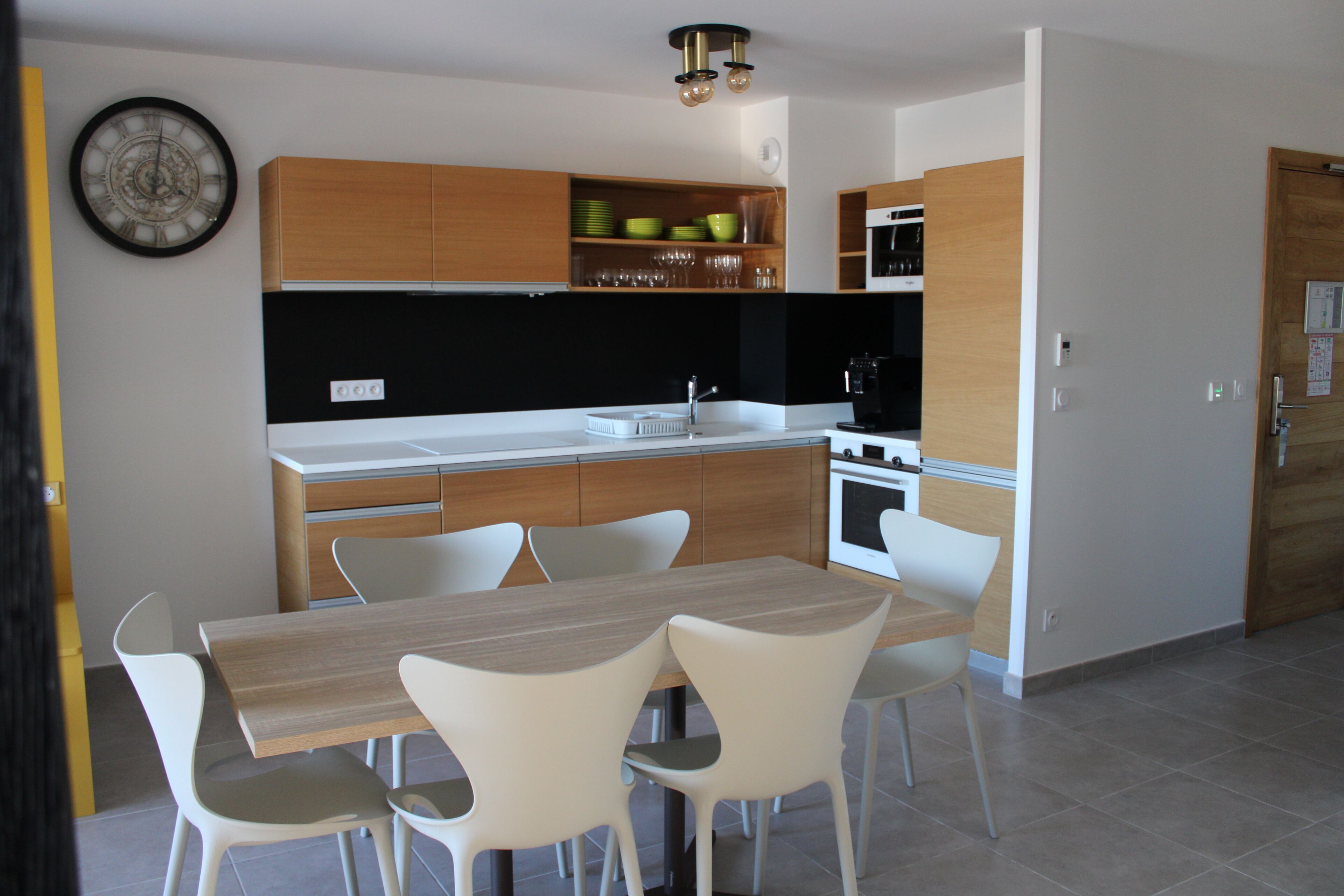 A modern kitchen with white cabinetry, a wooden countertop, and a dining area with white chairs.