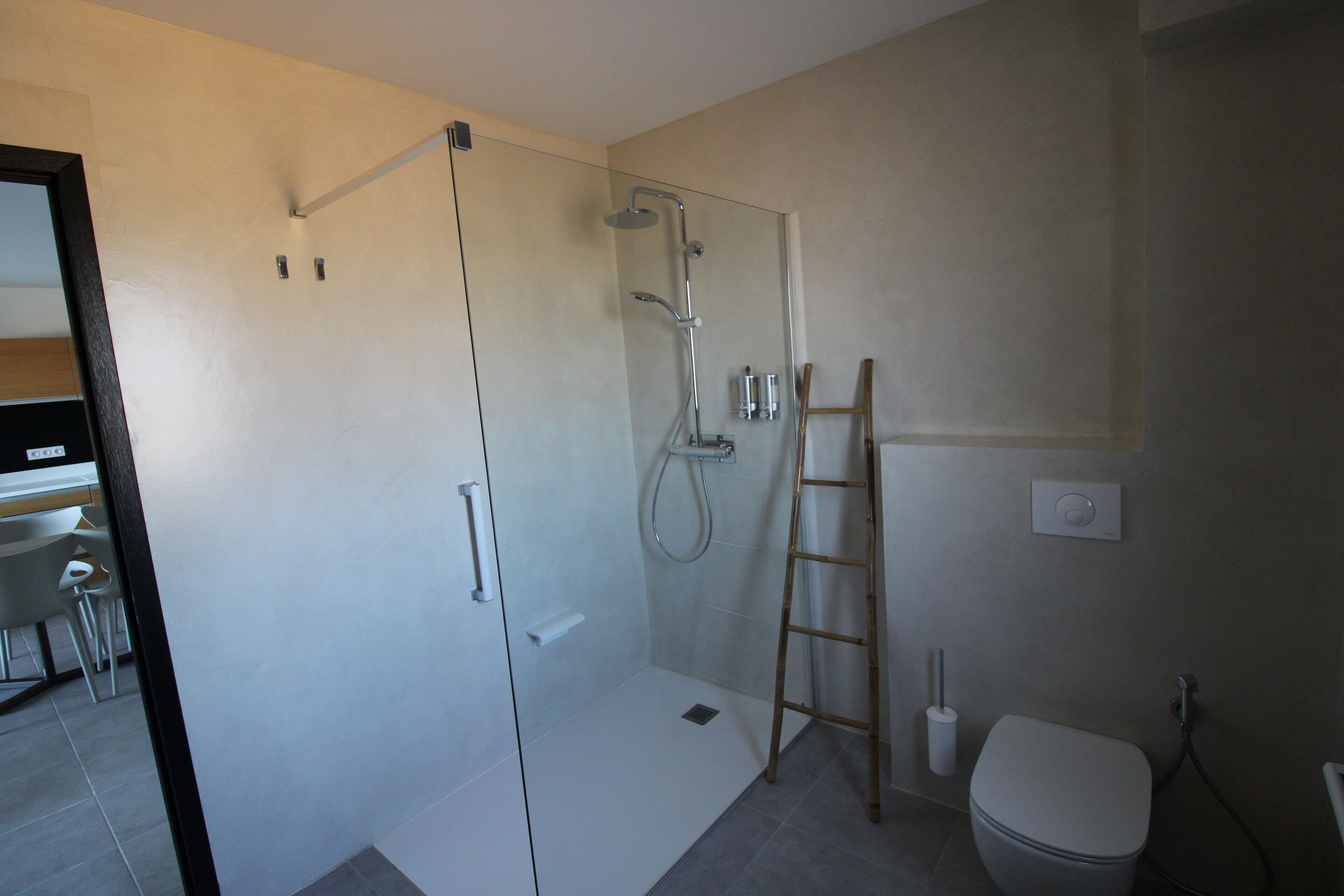 Een moderne badkamer met een glazen douchecabine, een toilet en een wastafel.