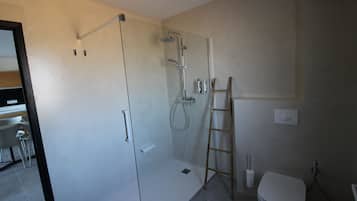 Een moderne badkamer met een glazen douchecabine, een toilet en een wastafel.