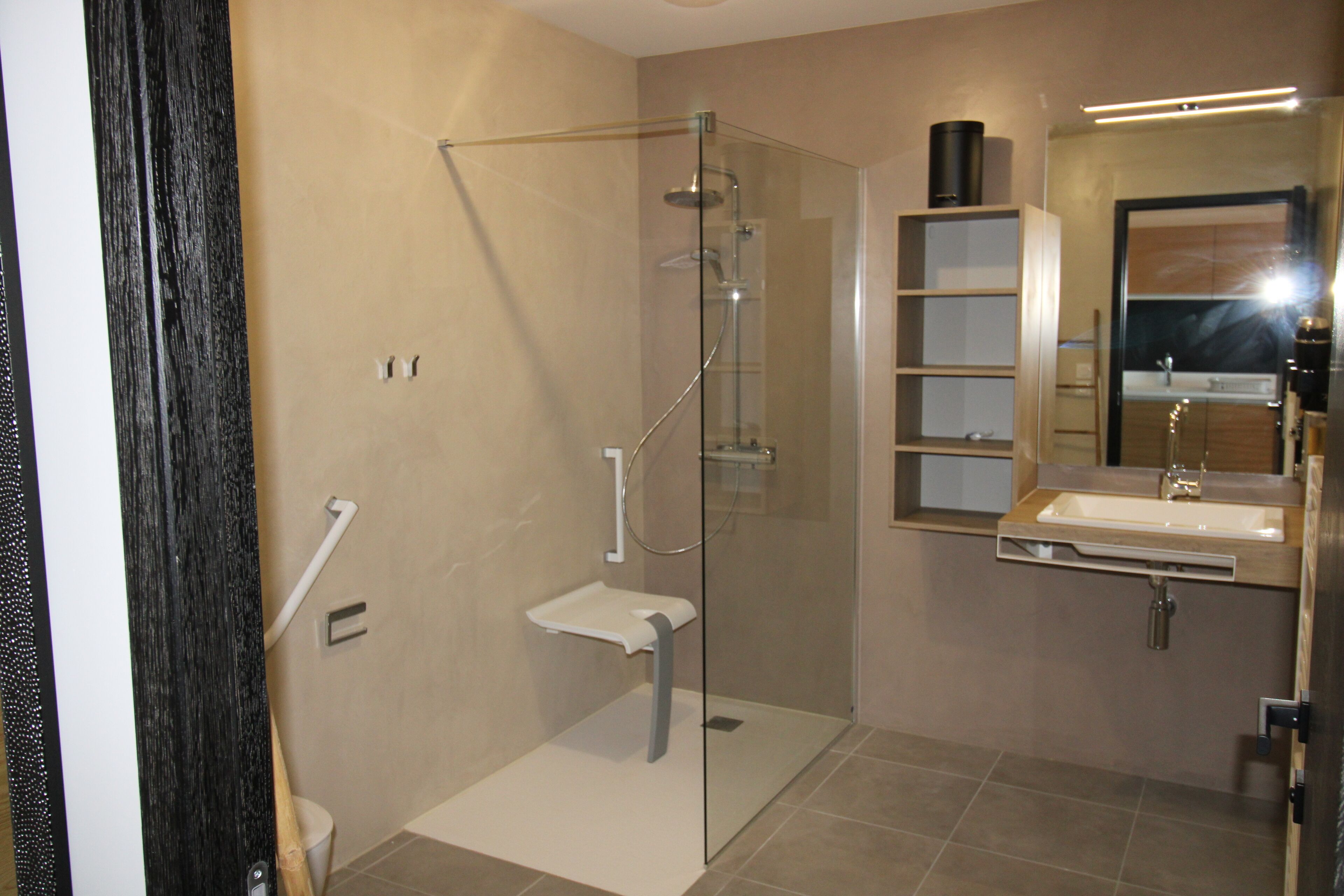 A modern bathroom with a glass-enclosed shower, a white sink, and a mirror above the sink.