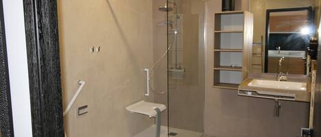 A modern bathroom with a glass-enclosed shower, a white sink, and a mirror above the sink.