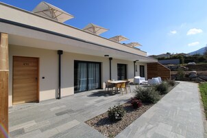 Un edificio moderno con un patio que cuenta con asientos al aire libre, una puerta de madera con la etiqueta