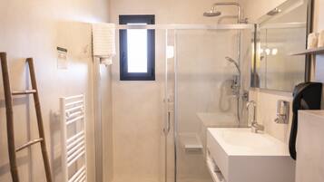 Un bany modern amb dutxa de vidre, un lavabo blanc i un vàter.