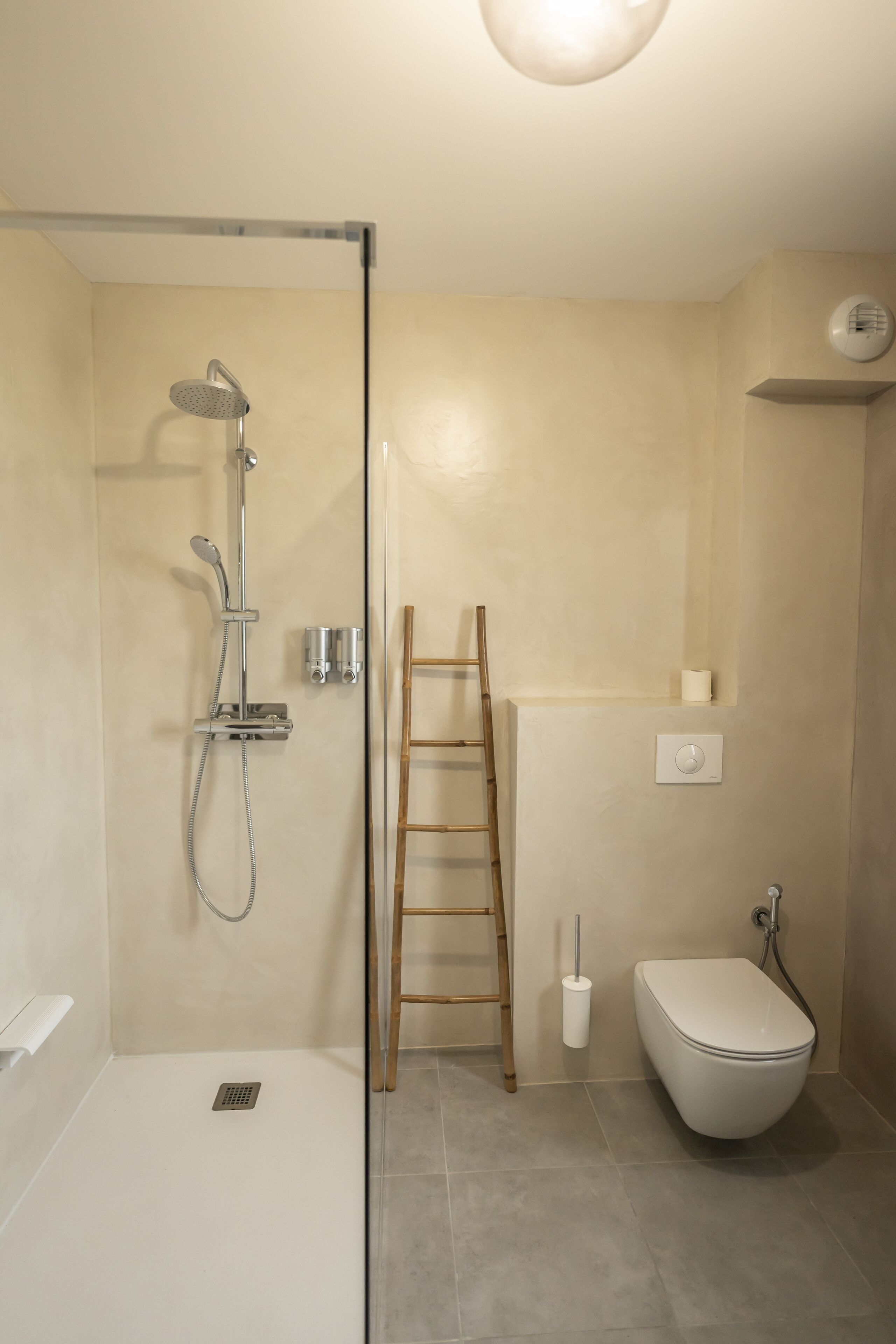 Un bagno moderno dotato di doccia, WC e una scala utilizzata come contenitore.