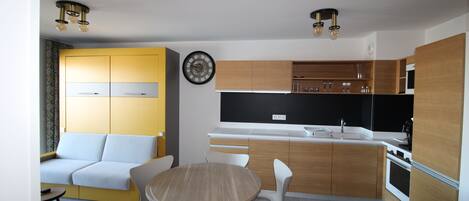 Una cocina moderna con armarios de madera, horno empotrado y comedor con una mesa redonda y sillas.
