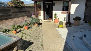A residential property with a concrete patio, potted plants, and a wooden deck. - Cozy Morro Bay Bungalo (Morro Bay)
