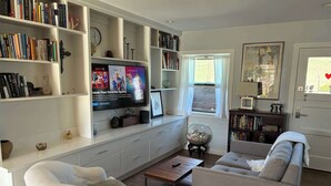 A living room with a television, bookshelves, a sofa, and a coffee table. - Cozy Morro Bay Bungalo (Morro Bay)