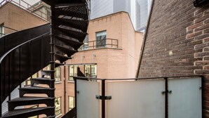 Un escalier en colimaçon mène à un espace sur le toit d’où l’on peut admirer un bâtiment en briques et une façade en verre.