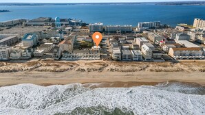Vista aérea de un pueblo costero con edificios, una torre de agua y una playa.