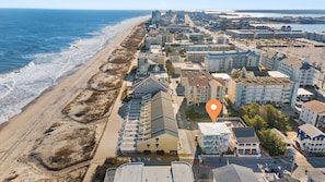 Vue aérienne d’une ville côtière avec des propriétés situées en bord de mer, dont un hôtel dont l’emplacement est clairement indiqué.