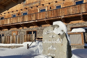 A wooden building with stone accents, a stone sign, and snow on the ground.