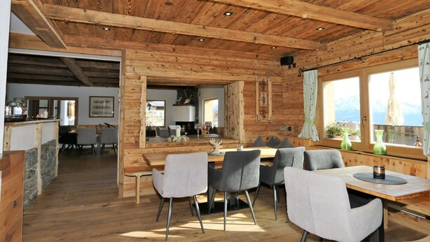 Un intérieur en bois comprenant un coin repas, une cuisine et de grandes fenêtres.