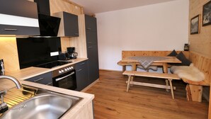 Une cuisine compacte dotée d’appareils électroménagers modernes, une table à manger en bois et un banc.