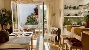 Una luminosa sala da pranzo con un tavolo apparecchiato per due, una panca e vista su un giardino attraverso una porta vetrata.
