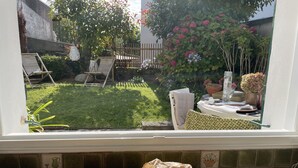 Una cucina con vista su un giardino sul retro, dotato di prato, terrazza in legno e una pianta in vaso.