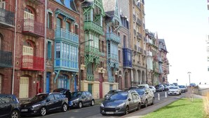 A row of colorful, historic buildings with balconies and parked cars along the street. - Townhouse near Bay of Somme and Norman Beaches (Rieux)