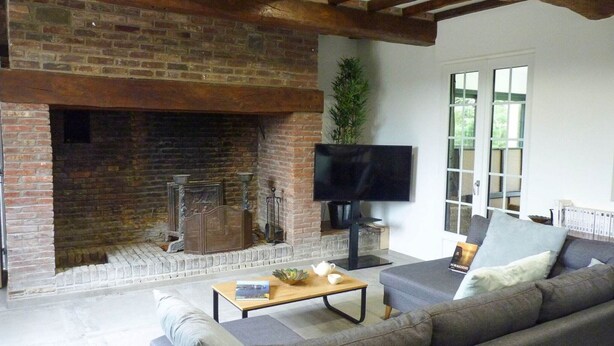 A living room with a brick fireplace, a flat-screen TV, a sofa, and a coffee table. - Townhouse near Bay of Somme and Norman Beaches (Rieux)
