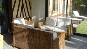 A modern outdoor seating area with wicker furniture and a glass door leading to a garden. - Townhouse near Bay of Somme and Norman Beaches (Rieux)