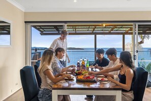 Un grupo de personas cenando en una mesa con vista al mar.