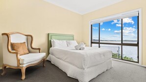 A room with a bed, a chair, and a large window with a view of the water. - Magical Views of Dee Why (Dee Why)
