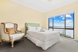 A room with a bed, a chair, and a large window with a view of the water. - Magical Views of Dee Why (Dee Why)