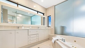 A modern bathroom with a large mirror, a bathtub, and a window. - Magical Views of Dee Why (Dee Why)