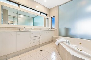 A modern bathroom with a large mirror, a bathtub, and a window. - Magical Views of Dee Why (Dee Why)