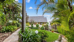 A house with a tiled roof, surrounded by a well-maintained garden with various plants and a stone pathway. - MAGICAL VIEWS OF DEE WHY (Dee Why)