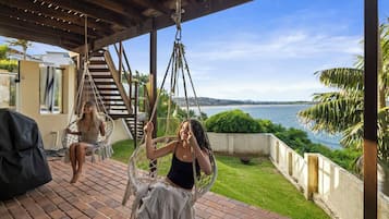 A covered outdoor area with a swing chair and a view of the sea.