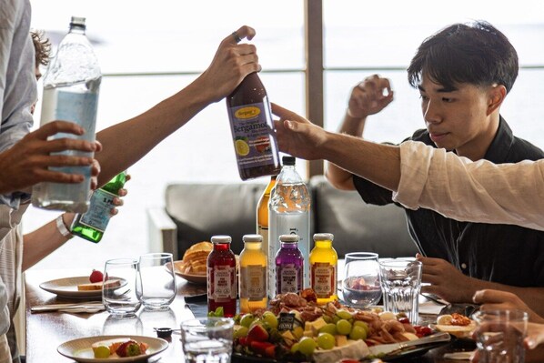 A group of people at a table with various food items and drinks, including bottles and glasses.