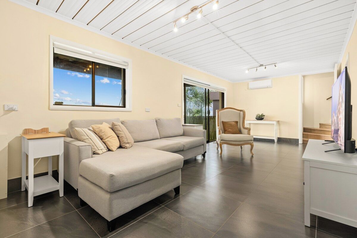 A modern living room with a sectional sofa, a small side table, a decorative chair, and a television.
