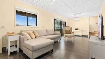 A modern living room with a sectional sofa, a small side table, a decorative chair, and a television.