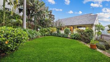 A house with a tiled roof, surrounded by a well-maintained lawn and various plants.