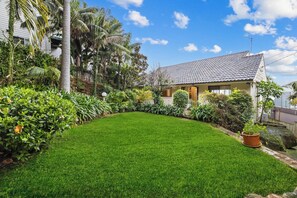 A house with a tiled roof, surrounded by a well-maintained lawn and various plants.