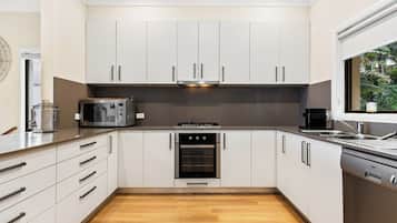 A modern kitchen with white cabinets, a built-in oven, a microwave, and a dishwasher.