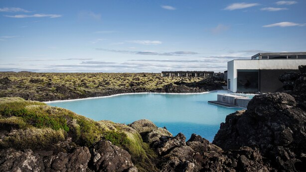 Ein modernes Gebäude mit einem Pool, umgeben von felsigem Gelände und vereinzelter Vegetation.